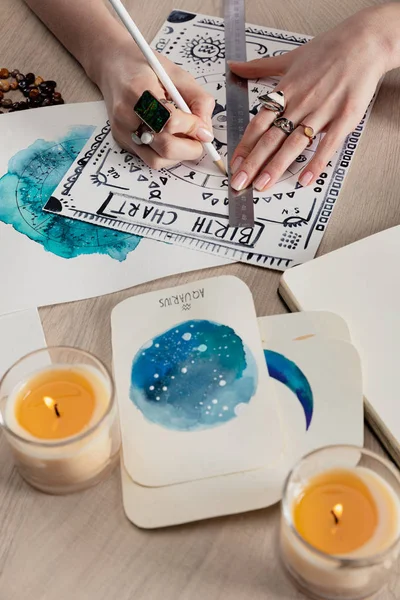 Concentration sélective de diseur de bonne aventure dessin carte de naissance par cartes avec aquarelle peintures et bougies sur la table — Photo de stock