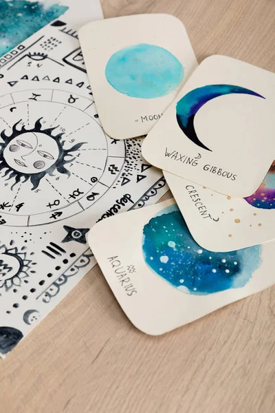 Cards with watercolor drawings of moon phases and birth cart with zodiac signs on table — Stock Photo
