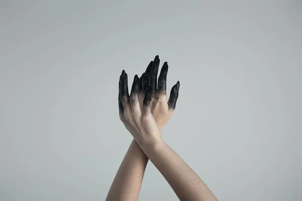 Vista recortada de manos de bruja en pintura negra aislada en gris - foto de stock
