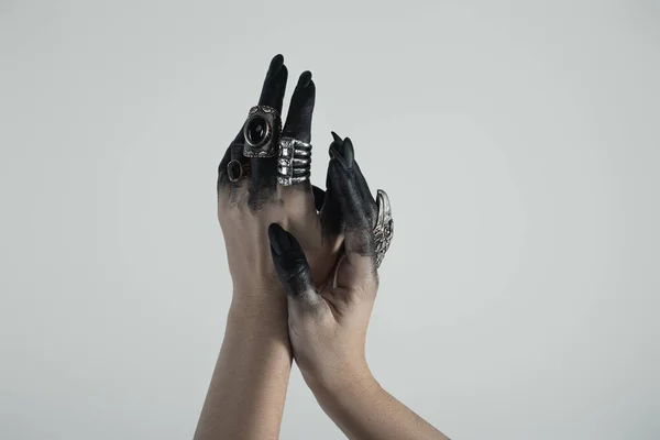 Обрезанный вид руки ведьмы в черной краске с ювелирными кольцами, изолированными на сером — стоковое фото