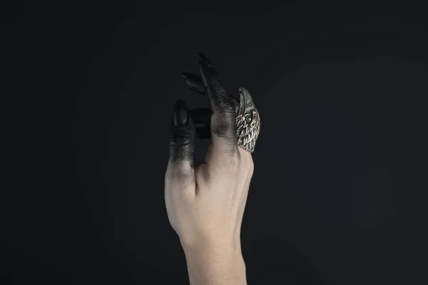 Cropped view of witch hand painted in black with jewelry ring isolated on black — Stock Photo