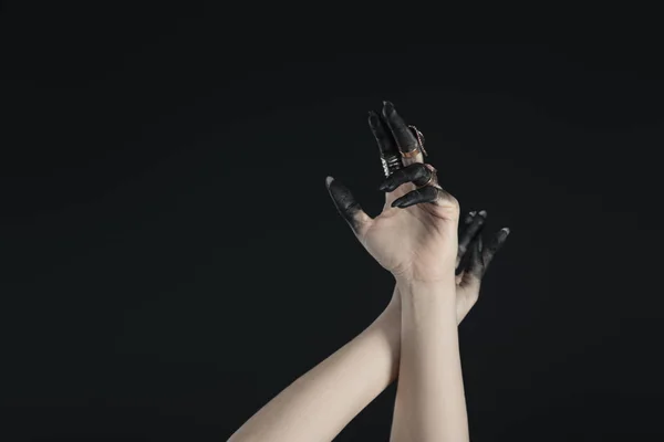 Cropped view of hands of witch with jewelry rings and black painted fingers isolated on black — Stock Photo