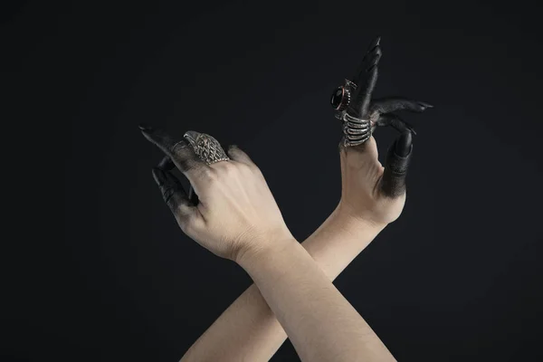 Cropped view of witch hands with jewelry rings and black paint isolated on black — Stock Photo