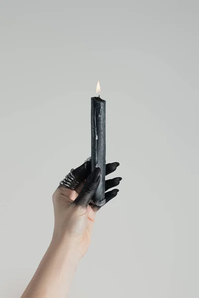 Vista recortada de la vela de celebración de bruja en mano pintada de negro aislada en gris - foto de stock
