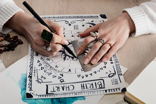 Vista ritagliata di astrologo disegno tabella di nascita con disegno ad acquerello sul tavolo — Foto stock