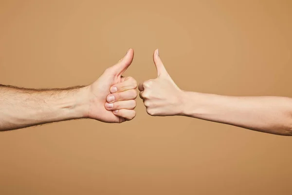Обрізаний вид чоловіка і жінки, що показує великі пальці вгору ізольовано на бежевому — стокове фото