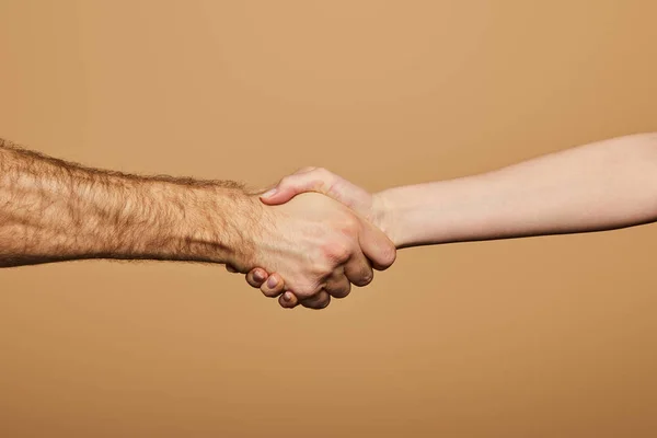 Vista recortada del hombre y la mujer estrechando las manos aislados en beige - foto de stock