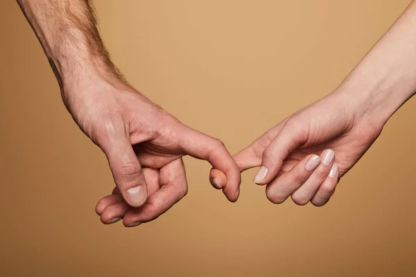 Abgeschnittene Ansicht von Mann und Frau, die Finger isoliert auf Beige halten — Stockfoto