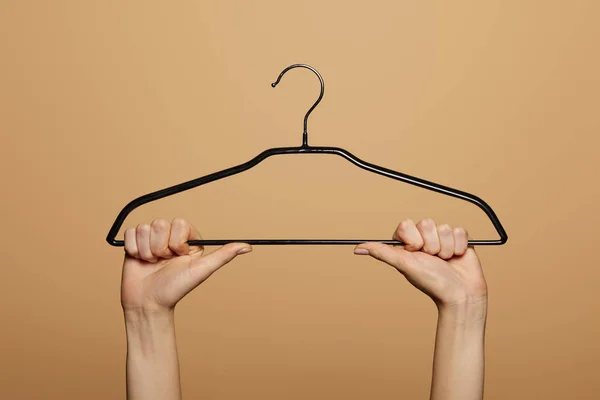 Cropped view of woman holding empty hanger isolated on beige — Stock Photo