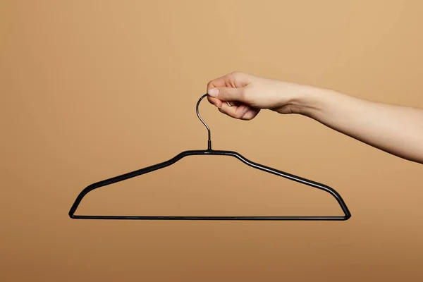 Cropped view of woman holding empty hanger isolated on beige — Stock Photo