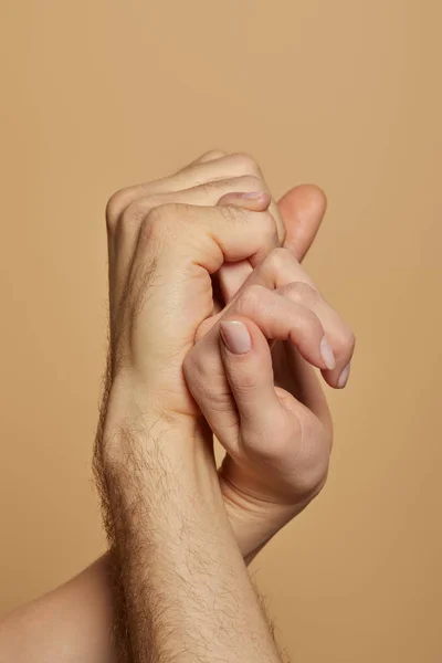 Cropped view of man and woman holding little fingers isolated on beige — Stock Photo