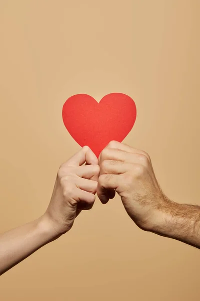 Vista ritagliata di uomo e donna con cuore rosso isolato sul beige — Foto stock