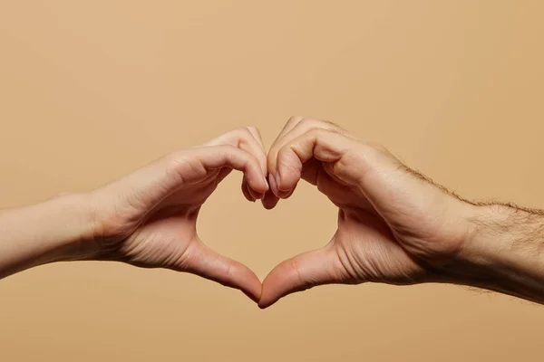 Cropped view of man and woman showing heart gesture isolated on beige — Stock Photo