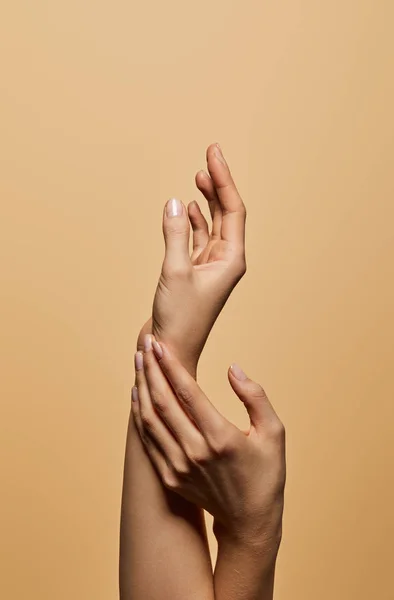 Vista recortada de las manos femeninas aisladas en beige - foto de stock