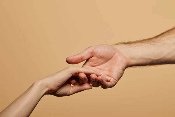 Vista recortada del hombre sosteniendo la mano de la mujer aislada en beige - foto de stock
