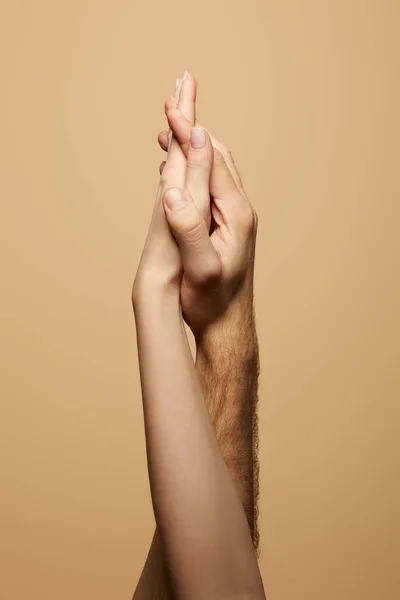 Vista parcial del hombre y la mujer tomados de la mano aislados en beige - foto de stock