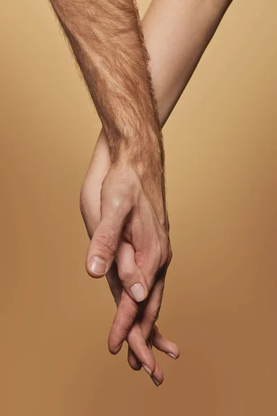 Partial view of man and woman holding hands isolated on beige — Stock Photo