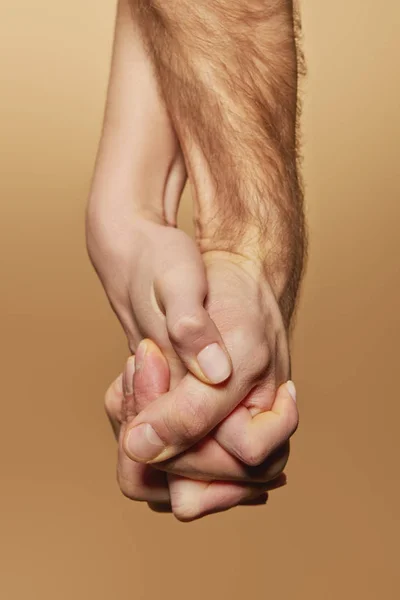 Partial view of man and woman firmly holding hands isolated on beige — Stock Photo