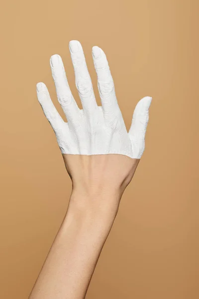 Vista recortada de la mujer con la mano pintada de blanco aislado en beige - foto de stock
