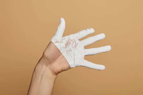 Abgeschnittene Ansicht einer Frau mit weiß bemalter Hand, die Handfläche isoliert auf beige zeigt — Stockfoto