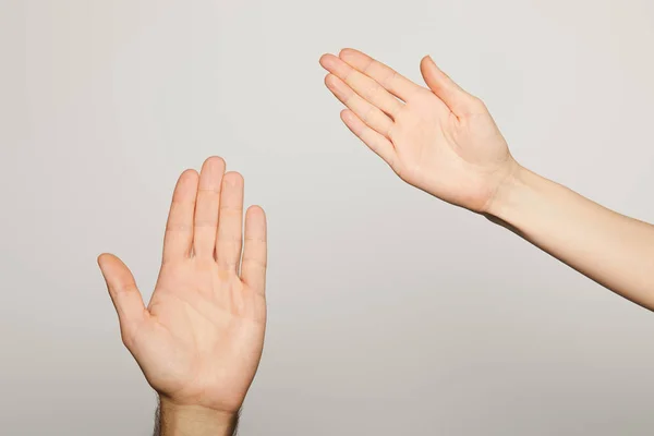 Vista ritagliata di uomo e donna che mostra palme isolate sul grigio — Foto stock