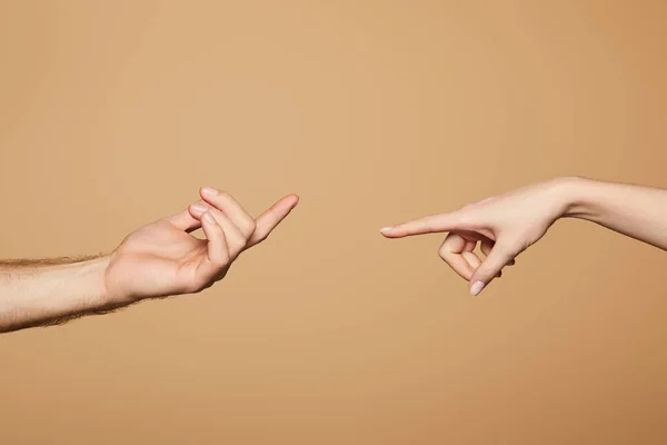 Обрізаний вид чоловіка і жінки, що досягає один одного пальцями ізольовані на бежевому — стокове фото
