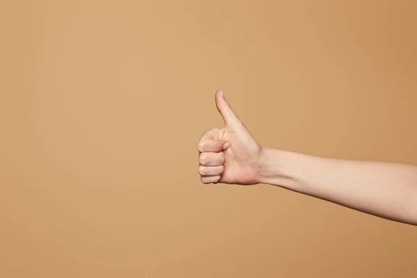 Ausgeschnittene Ansicht einer Frau, die vereinzelt den Daumen nach oben auf beige zeigt — Stockfoto