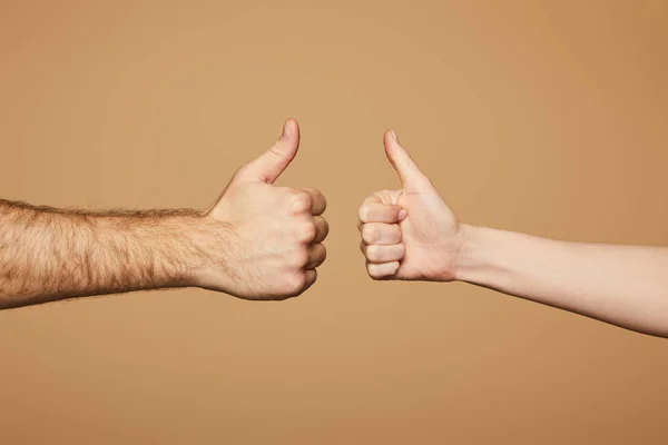 Recortado vista de hombre y mujer mostrando pulgares hacia arriba aislado en beige - foto de stock