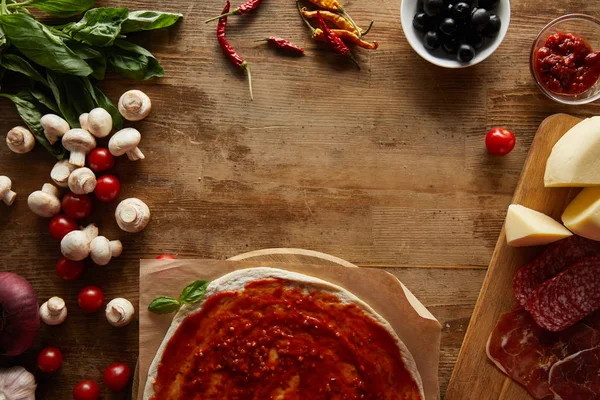 Vista superior da pizza e ingredientes em torno de fundo de madeira — Fotografia de Stock