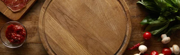 Top view of cutting board with ingredients for pizza on wooden background, panoramic shot — Stock Photo