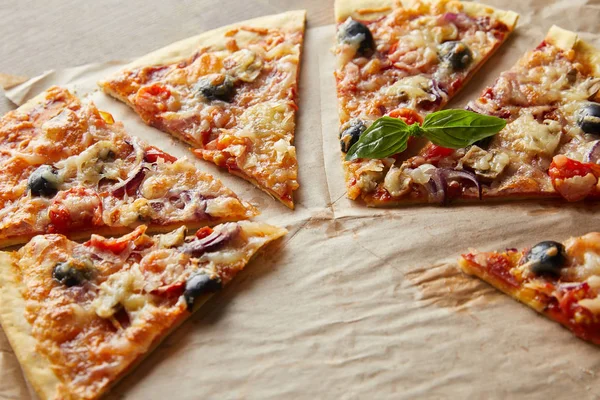 Leckere italienische Pizza mit Oliven auf Backpapier auf Holztisch schneiden — Stockfoto