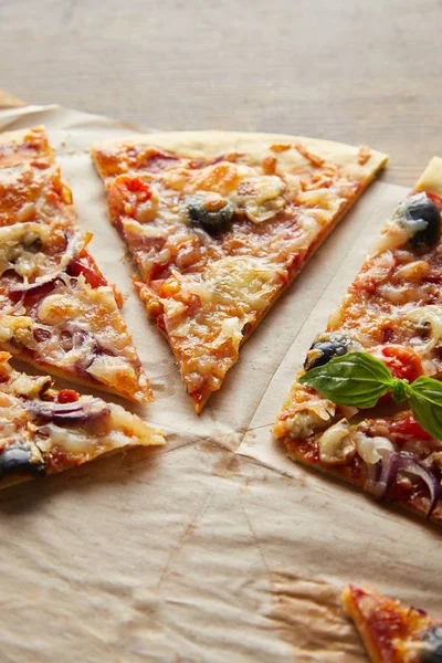 Cortar deliciosa pizza italiana con aceitunas sobre papel de hornear sobre mesa de madera - foto de stock