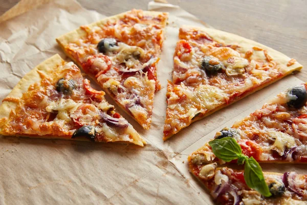 Leckere italienische Pizza mit Oliven auf Backpapier auf Holztisch schneiden — Stockfoto