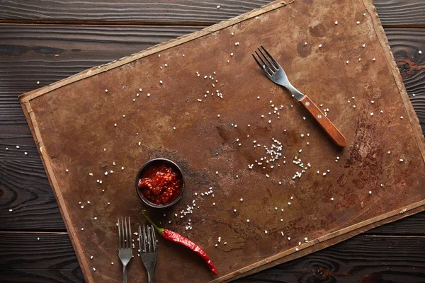 Vista dall'alto di salsa di peperoncino con sale e forchette su tavola di pietra su superficie di legno — Foto stock