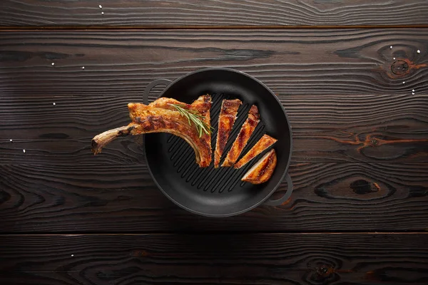 Vue du dessus de steak de côtelette savoureux dans une poêle avec du sel sur fond de bois — Photo de stock