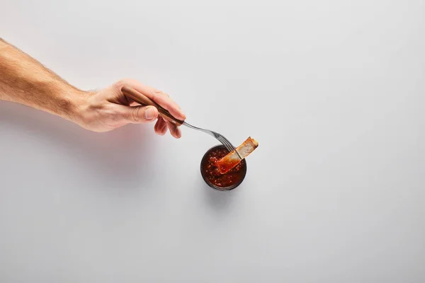 Top view of man putting steak slice in tomato sauce on white background — Stock Photo