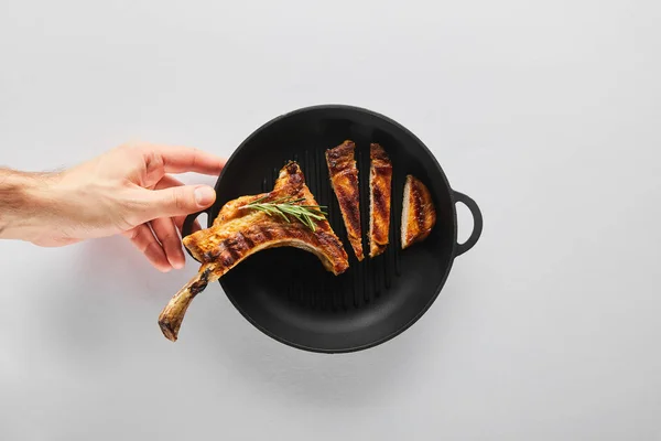 Top view of man holding frying pan with tasty ribeye steak on white background — Stock Photo