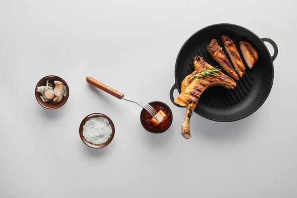 Top view of grilled ribeye steak with tomato sauce, garlic and salt on white background — Stock Photo