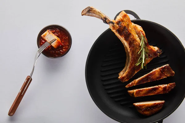 Вид сверху на вкусный стейк из рибея в сковороде с томатным соусом на белом фоне — стоковое фото