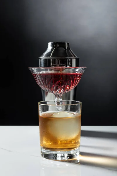 Vaso de whisky cerca de vino tinto y agitador en negro con humo - foto de stock