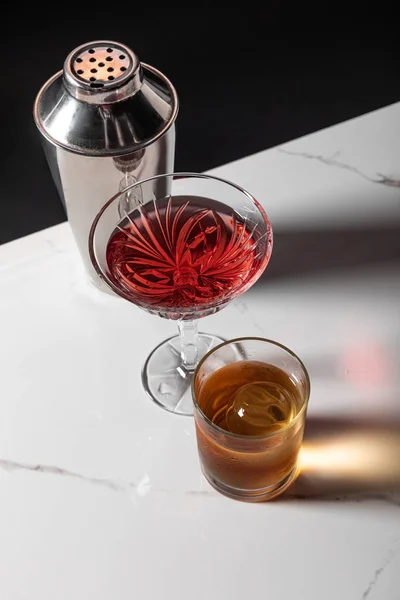 Vista dall'alto di bicchieri con bevande alcoliche vicino agitatore sulla superficie di marmo isolato su nero — Foto stock