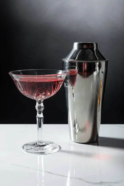 Verre avec vin rouge près shaker sur noir — Photo de stock