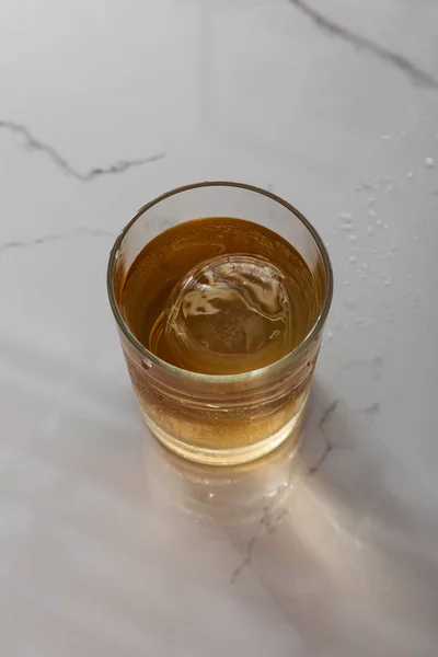 Vue de dessus du verre avec whisky sur la surface de marbre blanc — Photo de stock