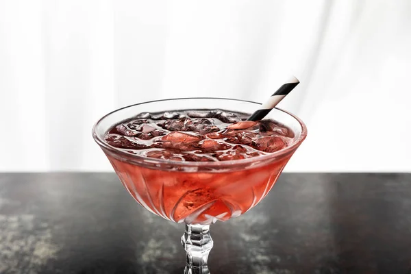 Red cocktail with striped straw and ice cubes on white — Stock Photo