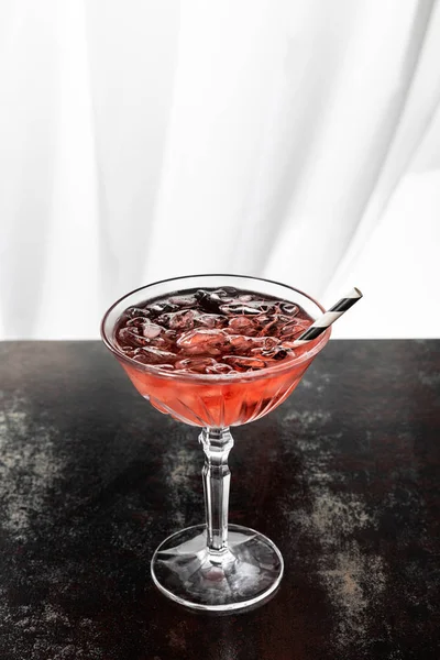 Cosmopolitan cocktail with striped straw and ice cubes on white — Stock Photo