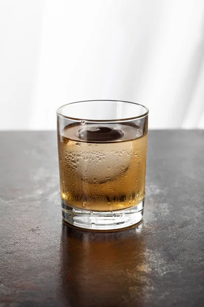 Vaso mojado con whisky y cubo de hielo sobre blanco - foto de stock