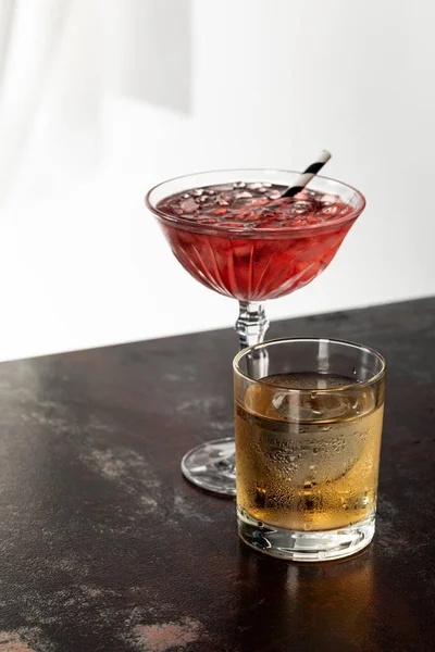 Glass of whiskey near red cosmopolitan cocktail on white — Stock Photo