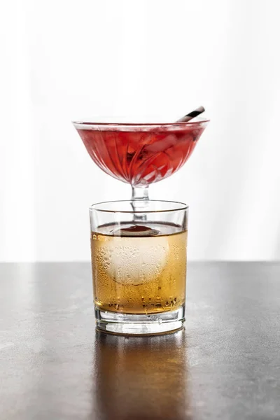 Wet glass with whiskey near red cosmopolitan cocktail on white — Stock Photo