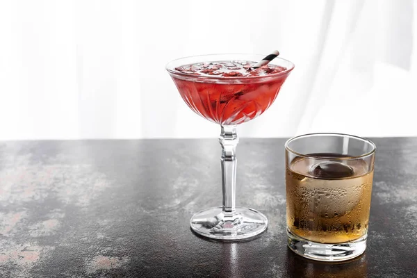 Bicchiere di whisky vicino a cocktail cosmopolita rosso con cubetti di ghiaccio su bianco — Foto stock