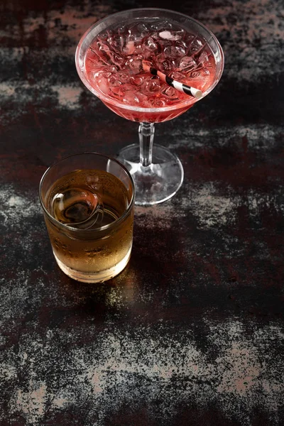 Top view of cosmopolitan cocktail near glass with whiskey on black surface — Stock Photo